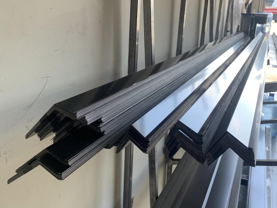Stacks of black metal trim profiles bent in Caliber's shop